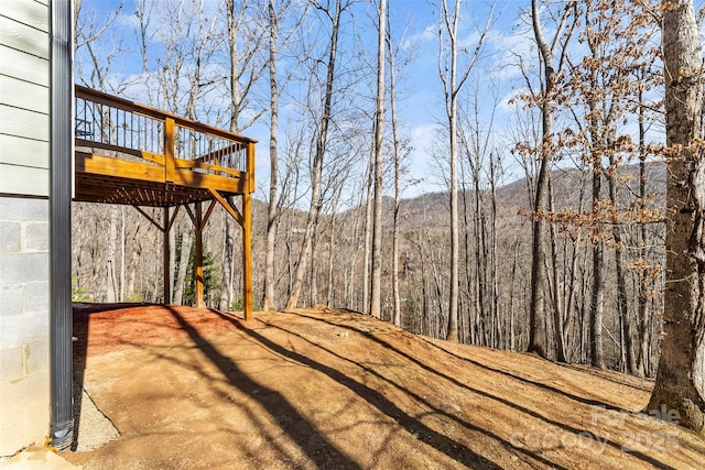 view of yard with a view of trees and a wooden deck