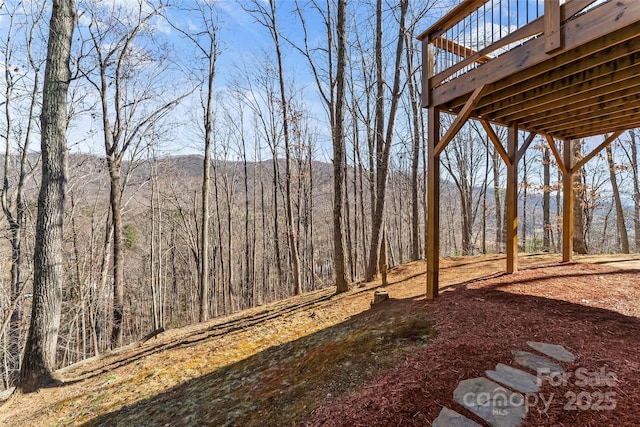 view of yard featuring a deck and a wooded view