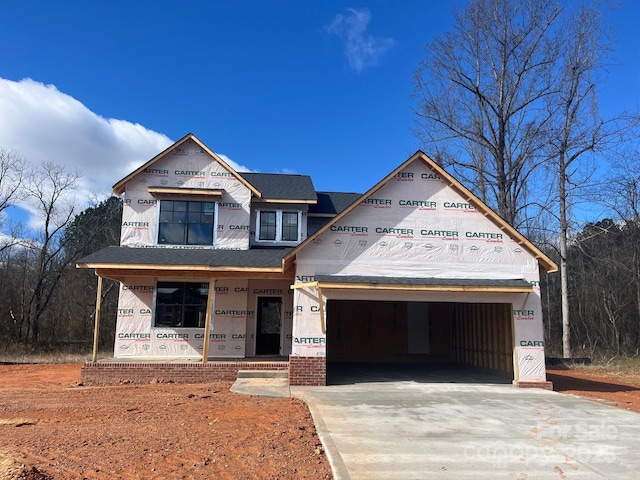 unfinished property featuring a garage, driveway, and a porch