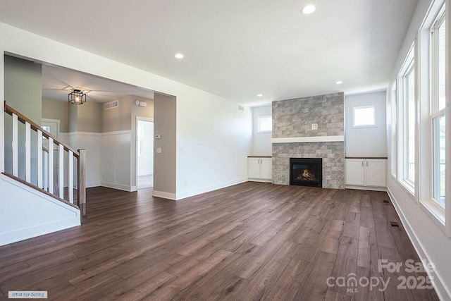 unfurnished living room with visible vents, dark wood-style floors, stairway, a fireplace, and recessed lighting