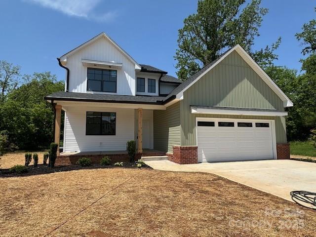1906 Maius Dr, Conover, NC 28613 - view of front of home with driveway, an attached garage, a porch, board and batten siding, and brick siding