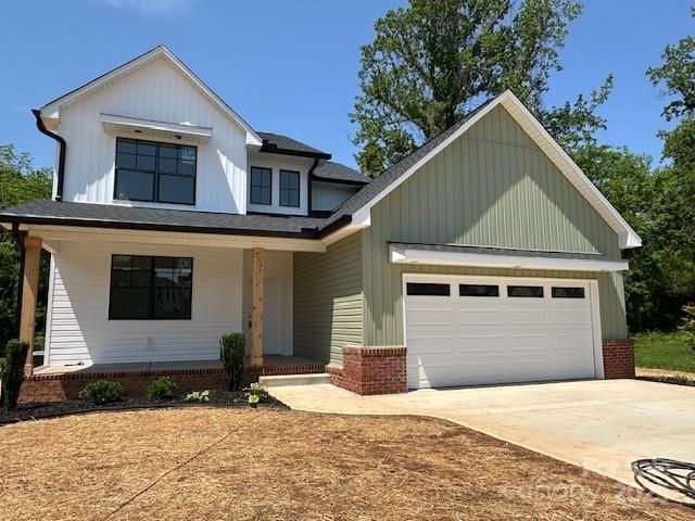 1906 Maius Dr, Conover, NC 28613 - view of front of house with covered porch, driveway, an attached garage, and board and batten siding