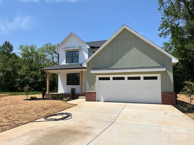 1906 Maius Dr, Conover, NC 28613 - modern inspired farmhouse featuring brick siding, driveway, a porch, board and batten siding, and a garage
