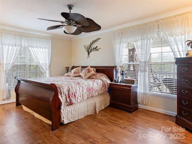 bedroom featuring multiple windows, a textured ceiling, wood finished floors, and ornamental molding