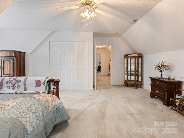 bedroom featuring visible vents, vaulted ceiling, light carpet, a closet, and a textured ceiling