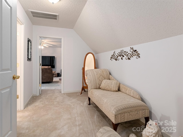 sitting room with visible vents, light carpet, lofted ceiling, a textured ceiling, and baseboards