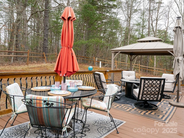 deck featuring a gazebo, outdoor dining area, and a fenced backyard