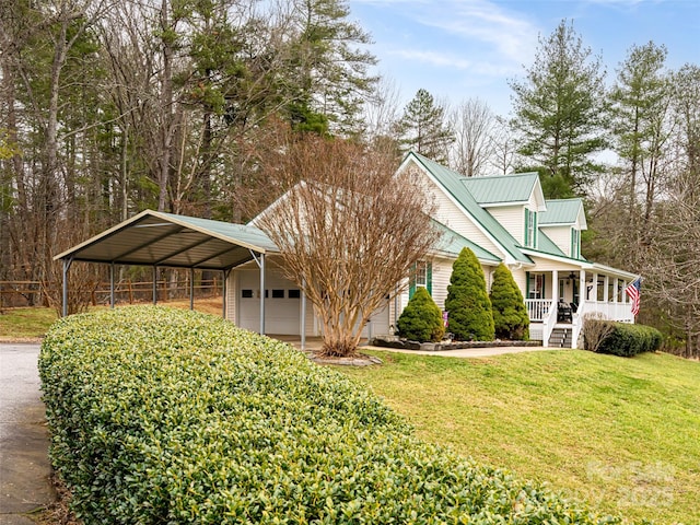 view of front of house with a garage, covered porch, a front yard, metal roof, and a carport