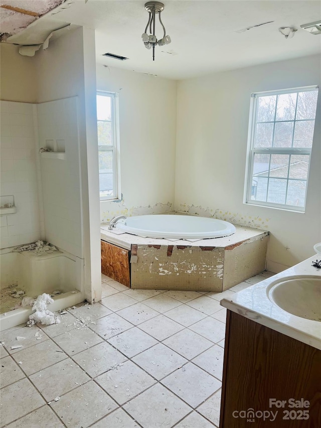 full bathroom featuring visible vents, a healthy amount of sunlight, vanity, and a garden tub