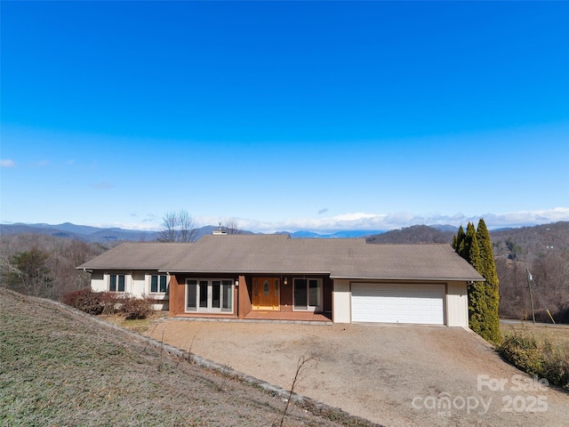 single story home featuring a garage, driveway, and a mountain view