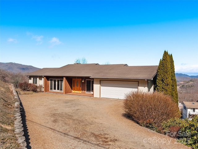 view of front of house with a garage, french doors, a mountain view, and dirt driveway