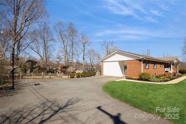 view of property exterior featuring a lawn, driveway, a gate, fence, and brick siding