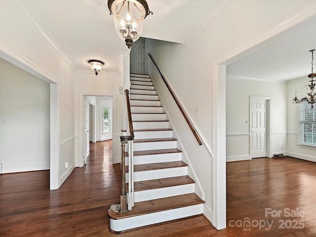 stairs with crown molding, a healthy amount of sunlight, a notable chandelier, and wood finished floors