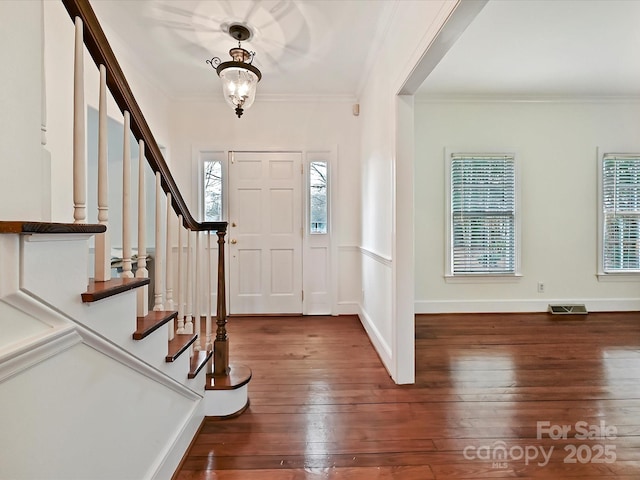 foyer entrance featuring hardwood / wood-style flooring, a wealth of natural light, and crown molding