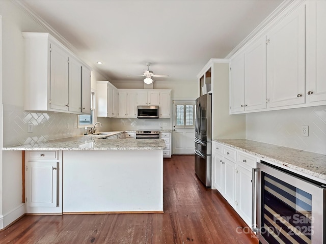 kitchen featuring appliances with stainless steel finishes, wine cooler, white cabinets, and a peninsula