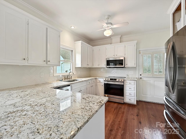 kitchen featuring white cabinets, appliances with stainless steel finishes, ornamental molding, light stone countertops, and a sink