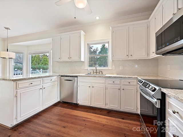 kitchen with dark wood finished floors, a peninsula, stainless steel appliances, white cabinetry, and a sink