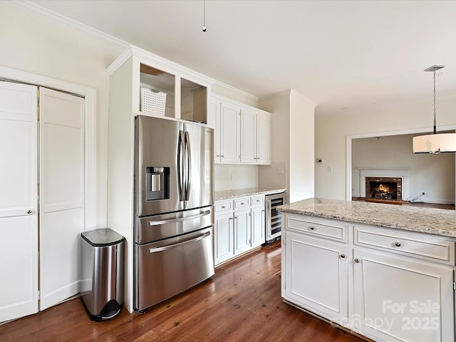 kitchen with stainless steel fridge, beverage cooler, white cabinets, dark wood-style flooring, and a brick fireplace