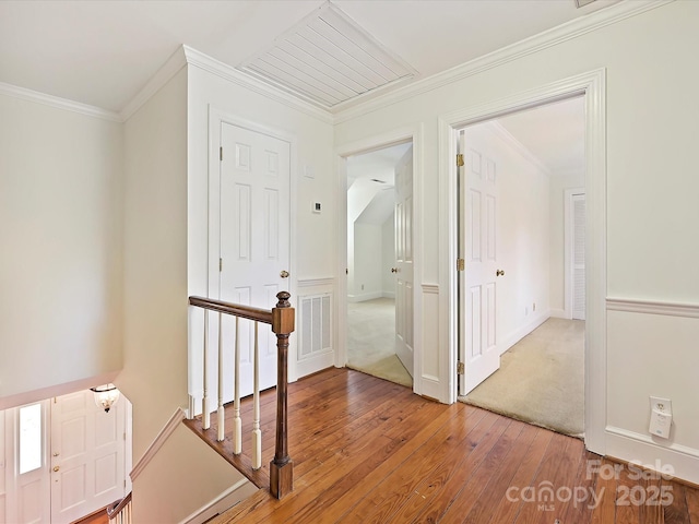 hall with hardwood / wood-style floors, an upstairs landing, visible vents, and crown molding