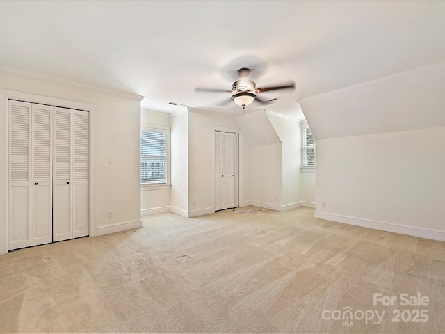 additional living space featuring a ceiling fan, light colored carpet, plenty of natural light, and baseboards