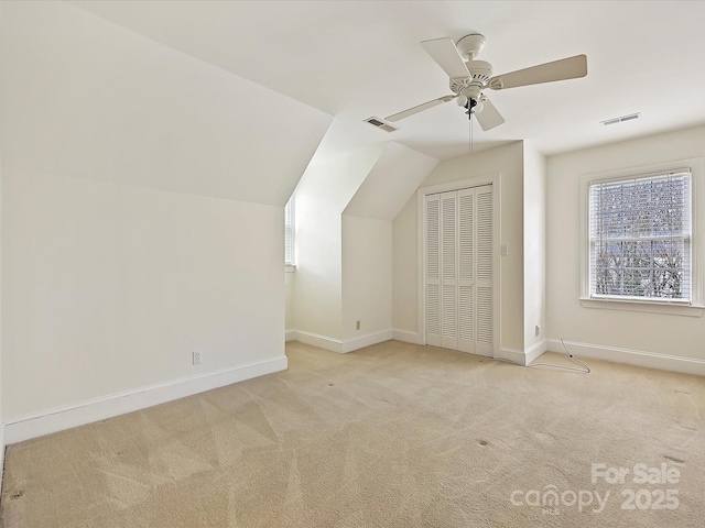 additional living space with carpet floors, visible vents, vaulted ceiling, and baseboards