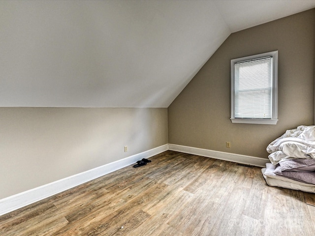 bonus room with vaulted ceiling, wood finished floors, and baseboards