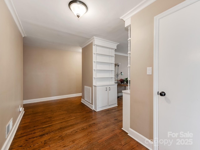 corridor with dark wood-style flooring, visible vents, crown molding, and baseboards