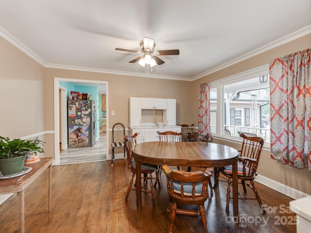 dining space featuring ornamental molding, wood finished floors, a ceiling fan, and baseboards