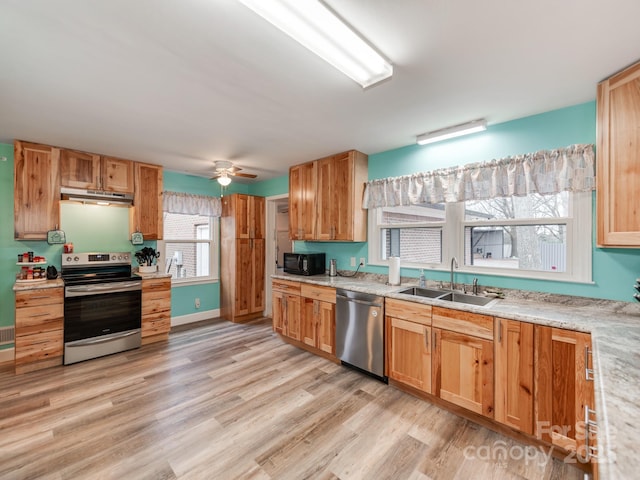 kitchen featuring under cabinet range hood, stainless steel appliances, a sink, and light countertops