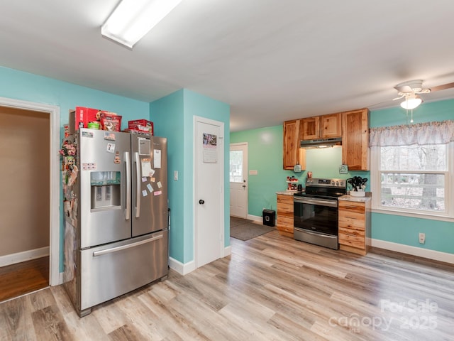 kitchen featuring under cabinet range hood, stainless steel appliances, baseboards, light countertops, and light wood-type flooring