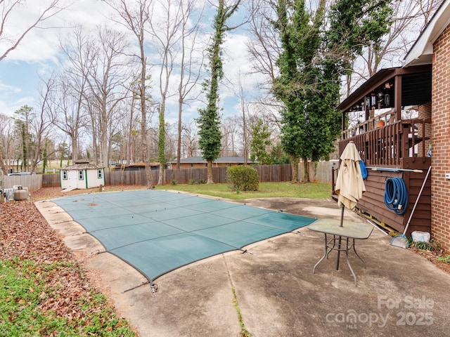 view of swimming pool featuring a fenced in pool, an outbuilding, a fenced backyard, and a patio