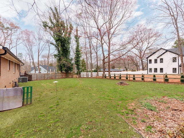 view of yard featuring central AC and fence