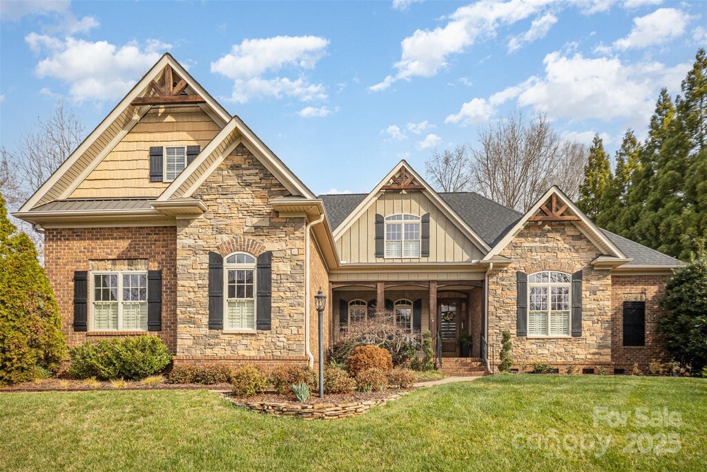 craftsman-style house featuring stone siding, board and batten siding, and a front yard