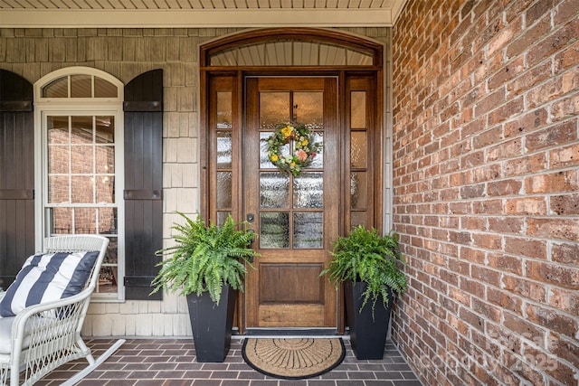 property entrance with a porch and brick siding