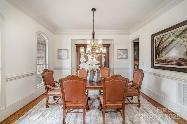 dining room featuring crown molding, a notable chandelier, wood finished floors, and visible vents