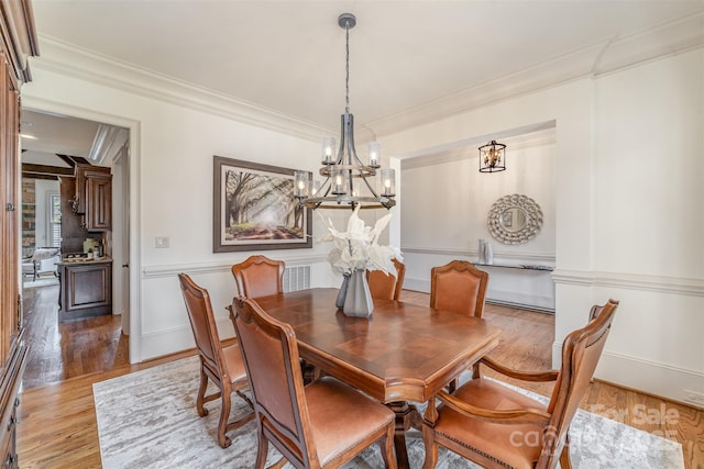 dining space featuring a chandelier, visible vents, light wood-type flooring, and ornamental molding