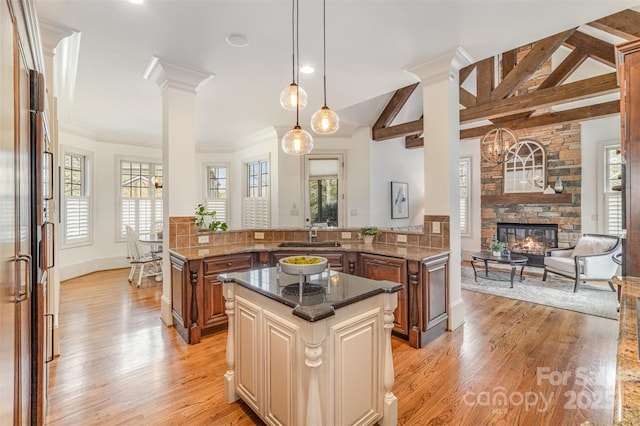 kitchen with a center island, lofted ceiling with beams, light wood-style flooring, a fireplace, and plenty of natural light