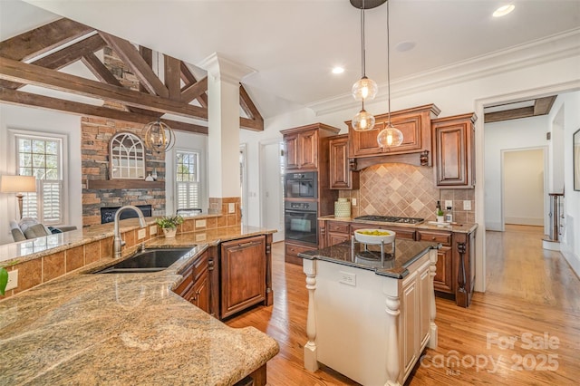 kitchen with light stone countertops, stainless steel gas cooktop, lofted ceiling with beams, a sink, and brown cabinets