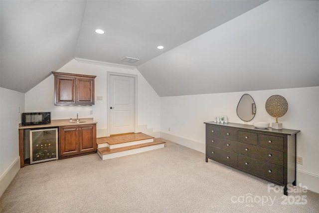 interior space featuring visible vents, light carpet, beverage cooler, recessed lighting, and vaulted ceiling