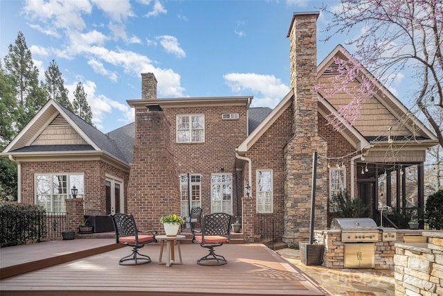 rear view of house with a wooden deck, brick siding, an outdoor kitchen, and a chimney