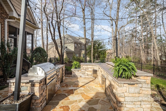 view of patio featuring grilling area, an outdoor kitchen, and fence