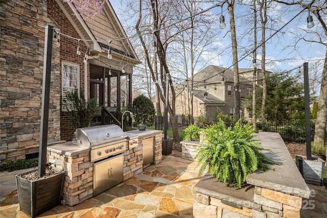 view of patio with area for grilling, fence, and an outdoor kitchen