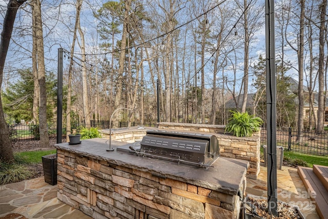 view of patio / terrace with a grill, exterior kitchen, and fence