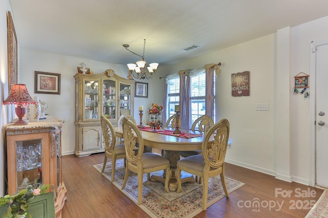 dining area with a chandelier, visible vents, baseboards, and wood finished floors