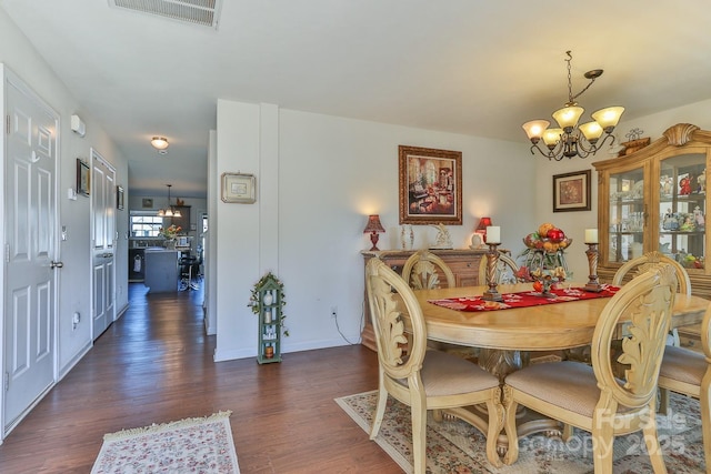 dining room with baseboards, dark wood-type flooring, visible vents, and a notable chandelier