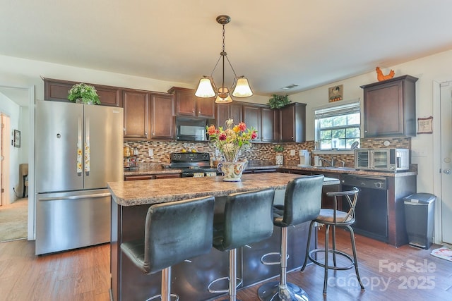 kitchen with tasteful backsplash, a kitchen island, black appliances, and wood finished floors