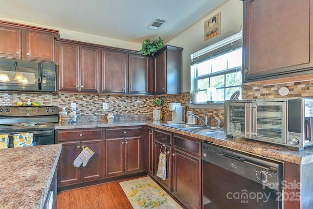 kitchen with visible vents, backsplash, a sink, light wood-type flooring, and black appliances