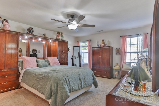 bedroom with light carpet, ceiling fan, and visible vents