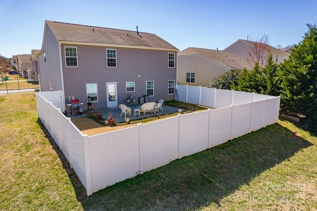 back of house with a fenced backyard, a lawn, and a patio