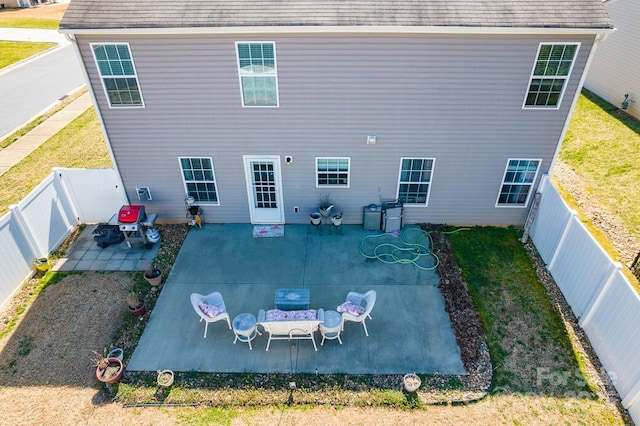 back of house with a shingled roof, a fenced backyard, a patio, and a lawn